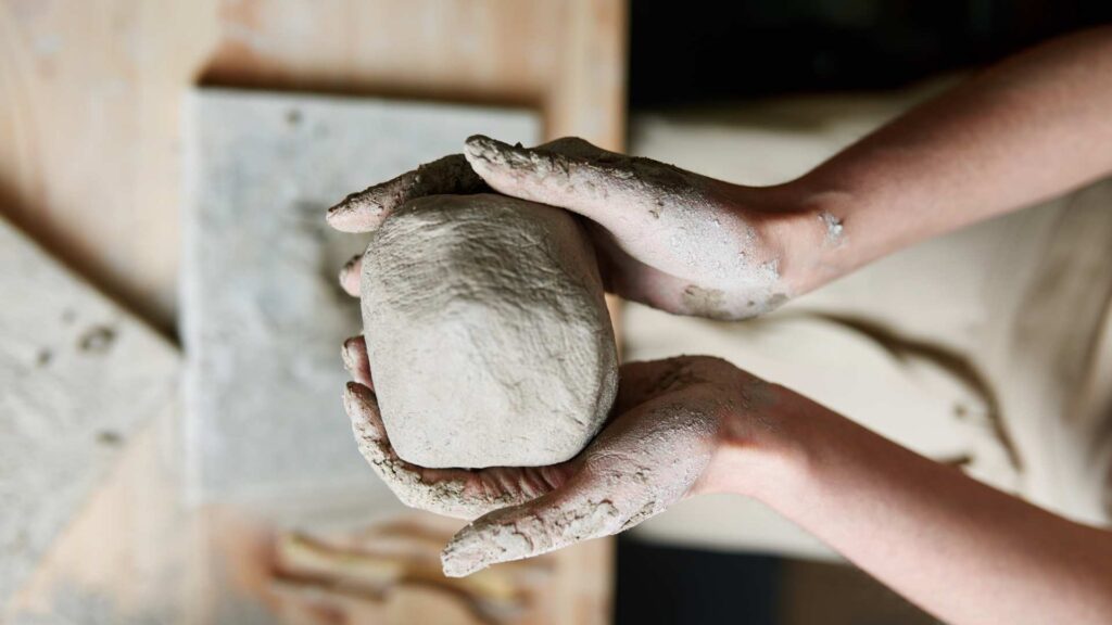Handen met een lomp klei