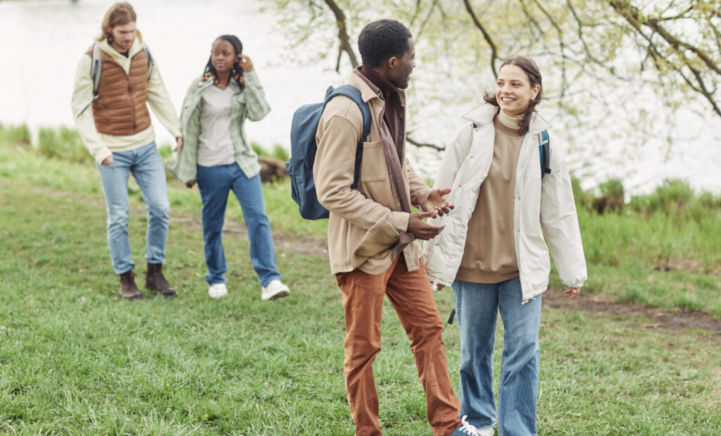 Two young multiethnic couple enjoying each other during their walk along the pond in the park